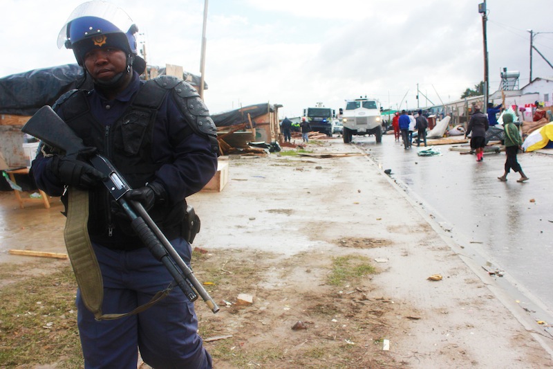 An armed police officer stands watch in Lwandle. (Ra'eesa Pather)