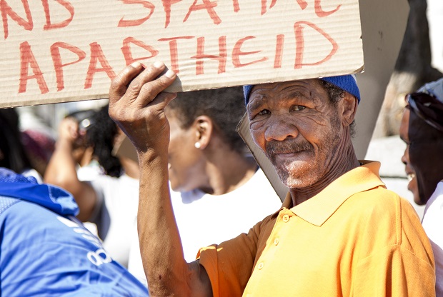 A local resident holds up a placard during the Bromwell Street eviction protest that reads, "Sorry for the inconvenience we're trying to end spacial apartheid"
