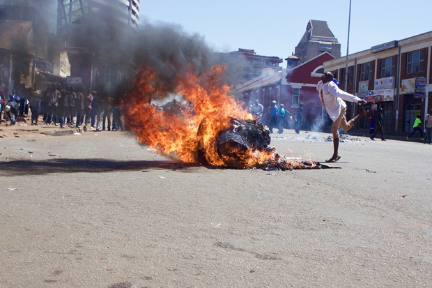 A protester dances by a fire on Jason Moyo Street, Harare.